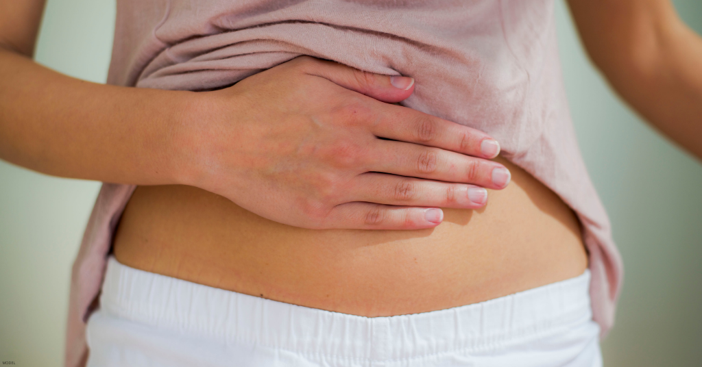 A woman touches her stomach after getting a tummy tuck.