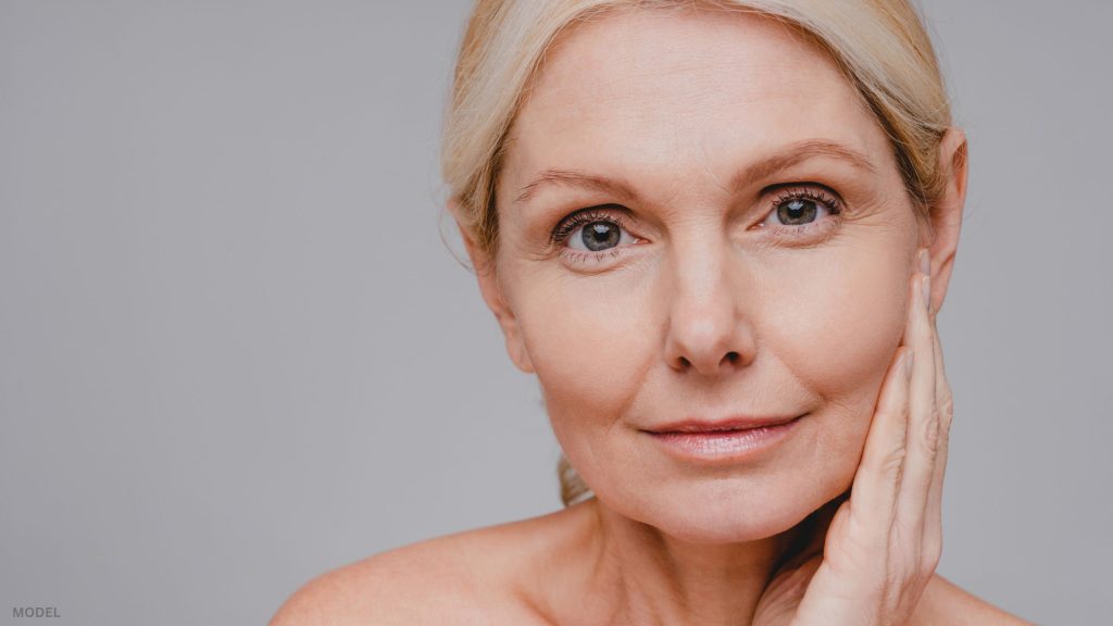Mature woman looking forward with hand on face (model)